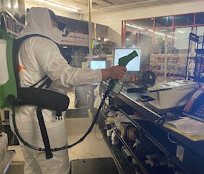 Team member in PPE cleaning a business.