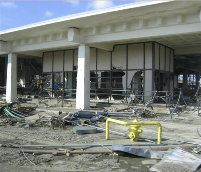Severely damaged exterior of a large commercial building after a storm.