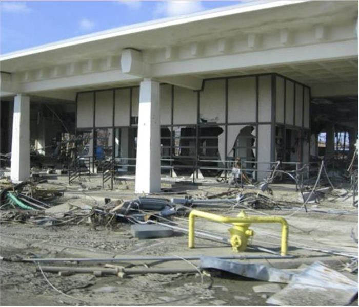 Exterior of a commercial building severely damaged by storm, broken windows, metal bars on floor