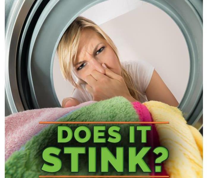 woman covering her nose while taking out clothes from washing machine