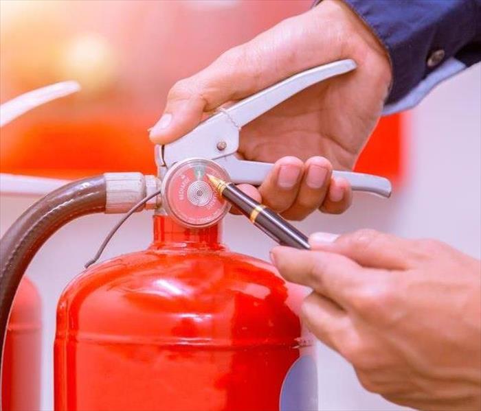 Hands holding a fire extinguisher.