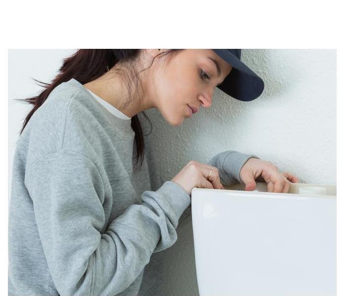 Woman checking the inside of a toilet tank